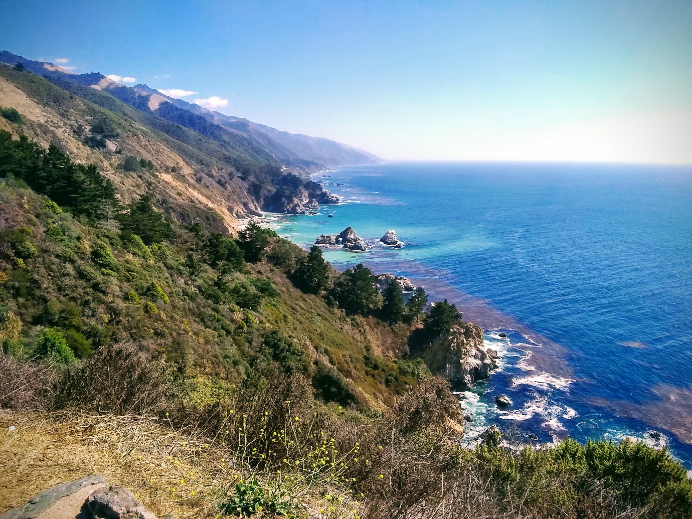 Sunny California coastline with turquoise water and rugged cliffs